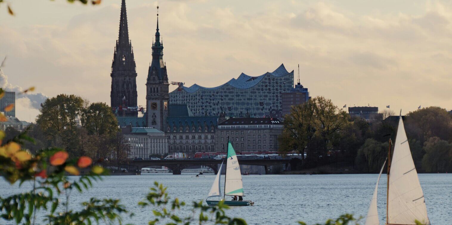 Sailing boats on Hamburg’s Alster Lake with the Elbphilharmonie and historic city skyline in the background.