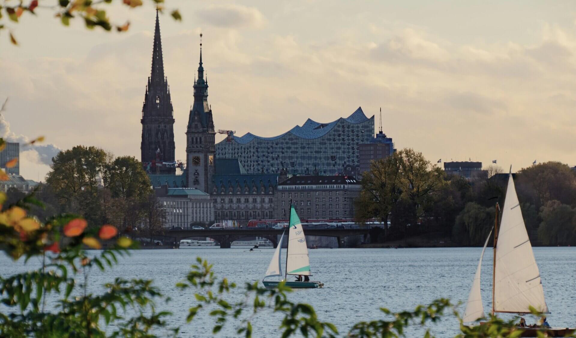 Sailing boats on Hamburg’s Alster Lake with the Elbphilharmonie and historic city skyline in the background.